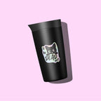 A matte black travel tumbler with a matching lid, featuring a cute cartoon cat graphic and the text 'Is he DEAD yet?' in a pastel gradient badge, set against a solid pink background.