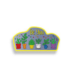 Decorative sticker in rainbow colors with potted plants and 'Be You' text on a white background