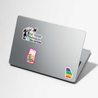 A silver laptop on a light gray background, decorated with three stickers: a black-and-white 'the future belongs to the curious' sticker, a pink and yellow 'Long Live The Librarian' book sticker, and a rainbow-striped state-of-Georgia silhouette sticker.