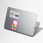 A silver laptop shown closed at an angle on a light gray background, with two library card stickers applied to the lid. One sticker is a standard white public library card with a raccoon photo and barcode, and the other is a colorful pink, yellow, and blue card that reads 'LONG LIVE THE PUBLIC LIBRARY'.
