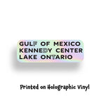 Holographic sticker that says "Gulf of Mexico," "Kennedy Center," and "Lake Ontario," highlighting the letters FDT for Fuck Donald Trump.